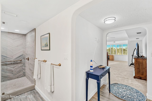 hall with hardwood / wood-style floors and a textured ceiling