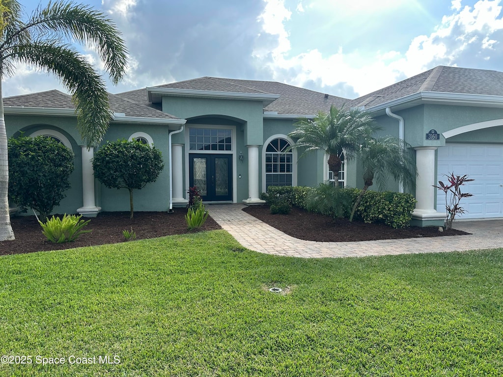 single story home featuring a garage, a front lawn, and french doors