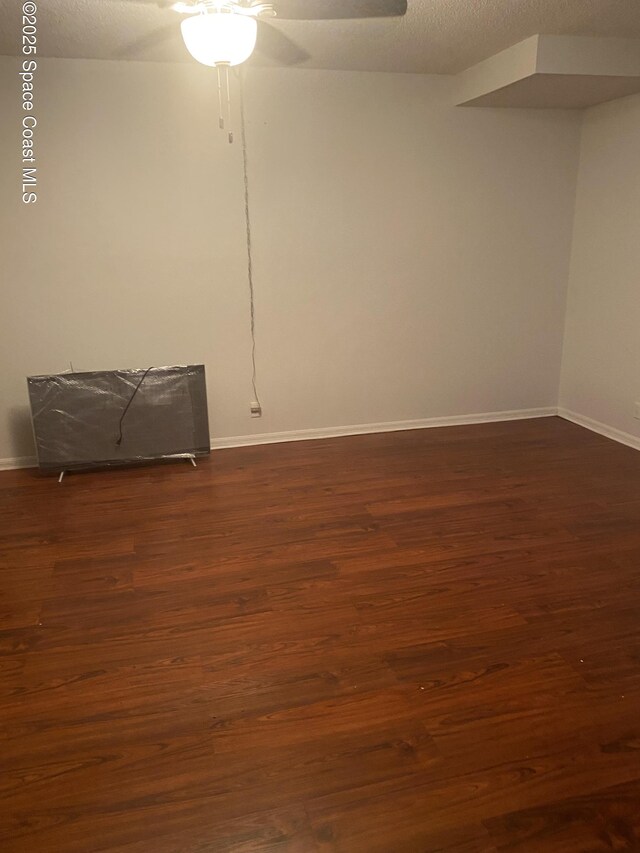 empty room with ceiling fan, dark hardwood / wood-style floors, and a textured ceiling