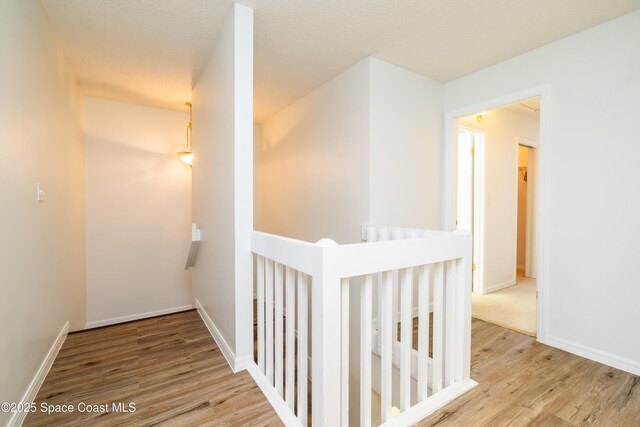 hallway with a textured ceiling and light wood-type flooring