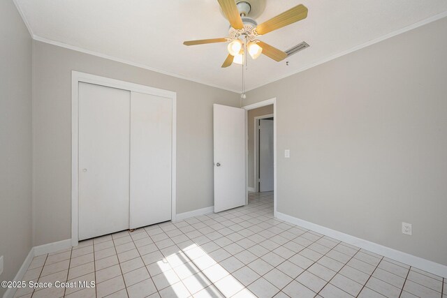 unfurnished bedroom featuring crown molding, light tile patterned flooring, ceiling fan, and a closet