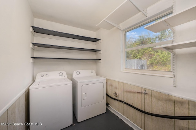 clothes washing area with washing machine and clothes dryer and wood walls