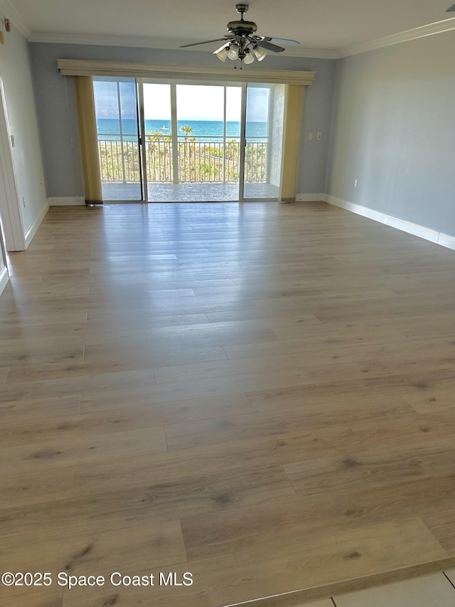 unfurnished room featuring ornamental molding, a water view, ceiling fan, and light wood-type flooring