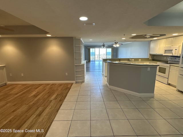 kitchen featuring light tile patterned flooring, a kitchen island, white cabinets, ceiling fan, and white appliances