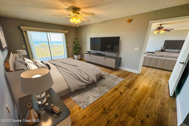 bedroom featuring ceiling fan, light hardwood / wood-style floors, a textured ceiling, and access to outside