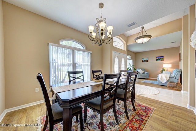 dining space with a chandelier, light wood-type flooring, and french doors