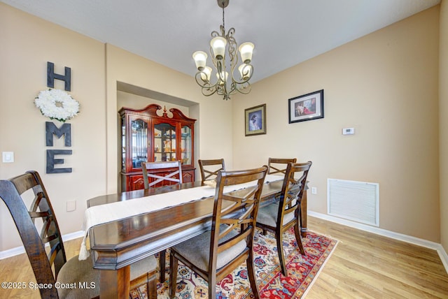 dining area with a notable chandelier and light hardwood / wood-style flooring