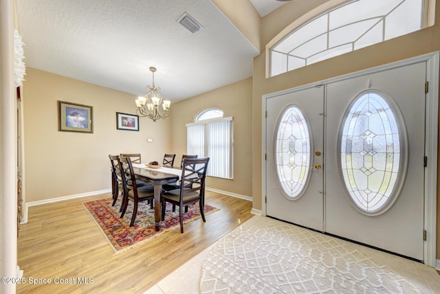 foyer featuring a chandelier, a textured ceiling, and light hardwood / wood-style floors