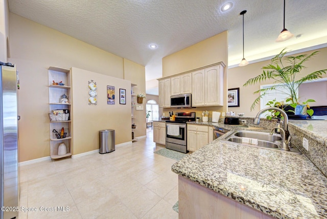 kitchen featuring sink, decorative light fixtures, a textured ceiling, light brown cabinets, and appliances with stainless steel finishes