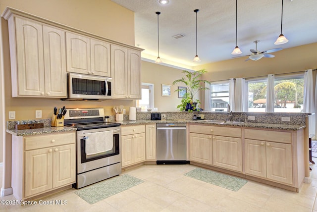 kitchen featuring stainless steel appliances, kitchen peninsula, sink, and hanging light fixtures