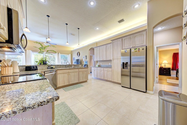 kitchen with sink, appliances with stainless steel finishes, hanging light fixtures, light stone countertops, and light brown cabinetry