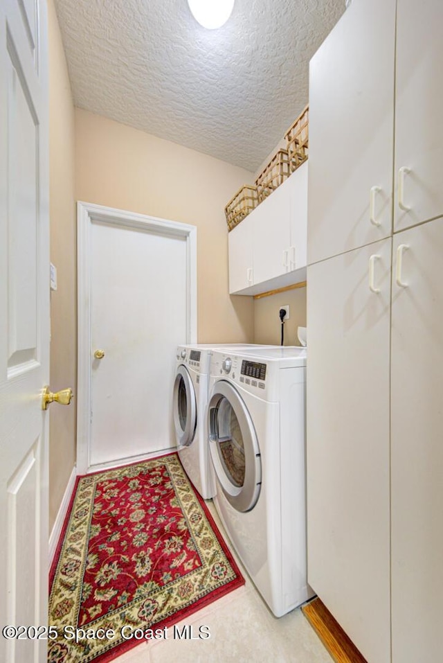 laundry area featuring cabinets, independent washer and dryer, and a textured ceiling