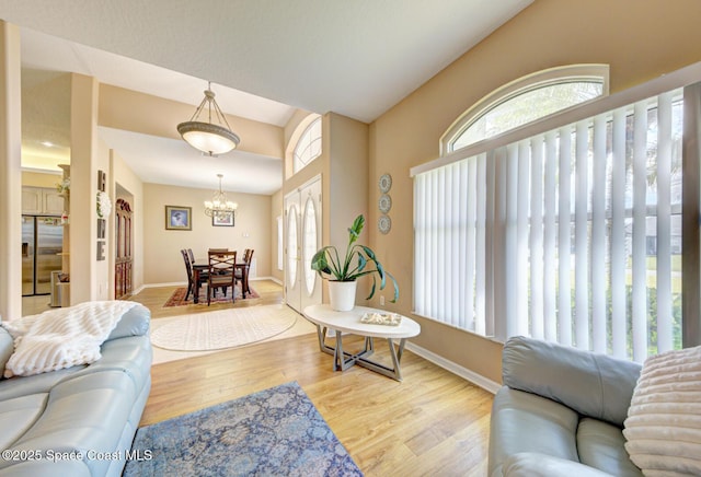 living room featuring an inviting chandelier, plenty of natural light, and light wood-type flooring