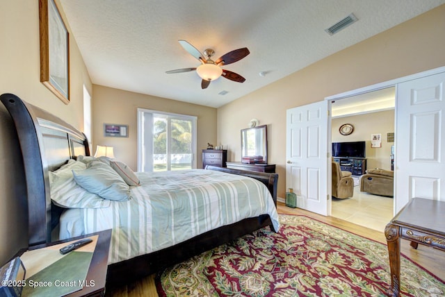 bedroom featuring ceiling fan, access to outside, a textured ceiling, and light hardwood / wood-style floors