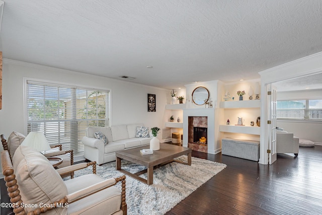 living room with dark hardwood / wood-style flooring, crown molding, built in features, and a textured ceiling