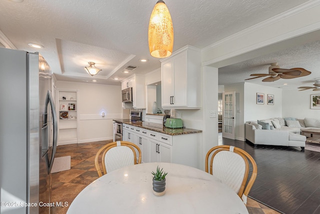 dining space featuring dark wood-type flooring, ornamental molding, a raised ceiling, and a textured ceiling