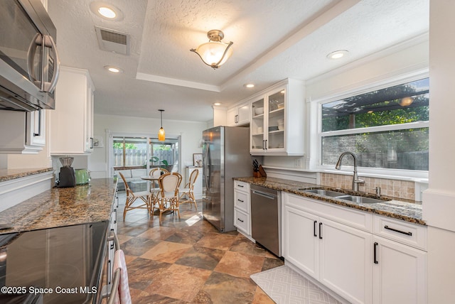 kitchen featuring sink, white cabinetry, decorative light fixtures, dark stone countertops, and appliances with stainless steel finishes