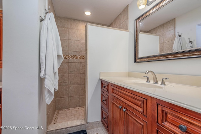 bathroom featuring tile patterned flooring, vanity, and a tile shower