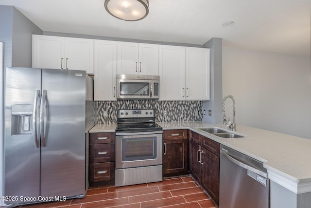 kitchen with white cabinetry, appliances with stainless steel finishes, sink, and kitchen peninsula