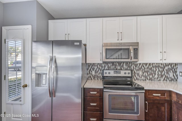 kitchen with dark brown cabinets, stainless steel appliances, decorative backsplash, and white cabinets