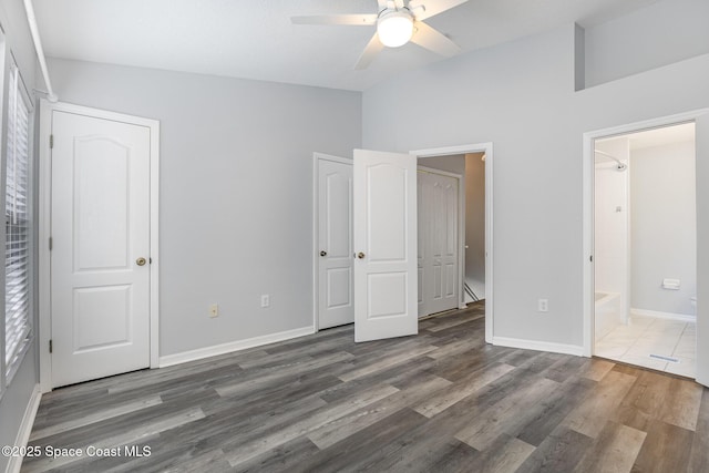 unfurnished bedroom featuring lofted ceiling, dark hardwood / wood-style floors, and ensuite bath