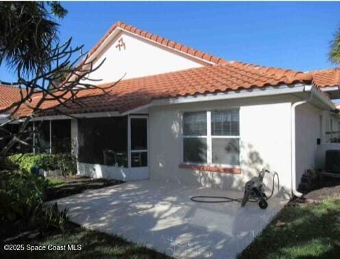 rear view of house with central AC unit and a patio