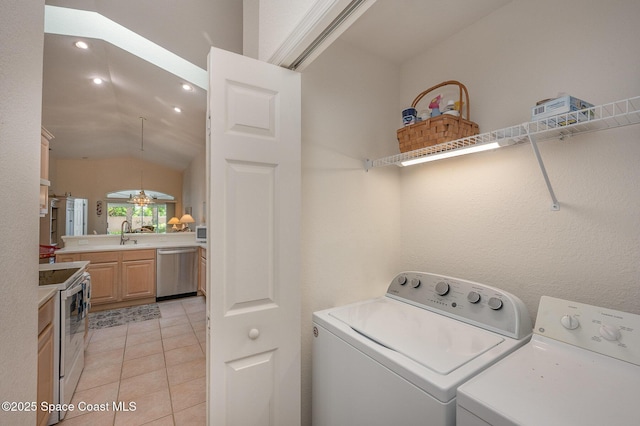 clothes washing area with sink, washer and dryer, and light tile patterned floors