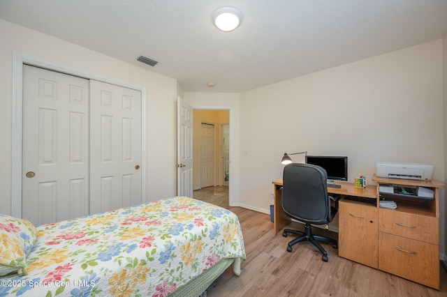 bedroom with light hardwood / wood-style flooring, a textured ceiling, and a closet