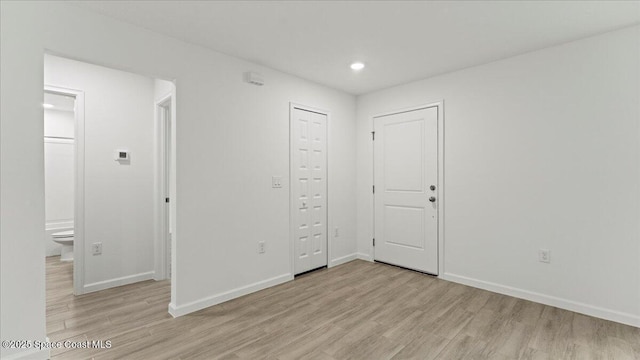 spare room featuring recessed lighting, light wood-style flooring, and baseboards