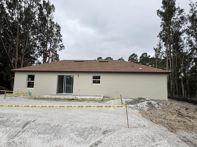 back of house featuring roof with shingles, a patio, and stucco siding