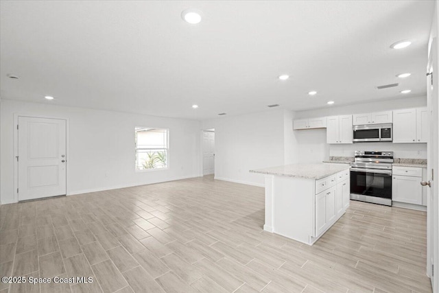 1305 Harper Blvd SW, Palm Bay, FL 32908 - kitchen with appliances with stainless steel finishes, recessed lighting, baseboards, open floor plan, and white cabinets