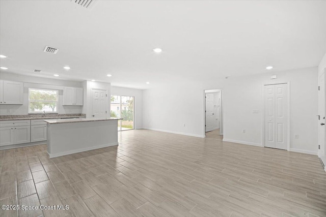 1305 Harper Blvd SW, Palm Bay, FL 32908 - kitchen featuring recessed lighting, a kitchen island, light wood-type flooring, open floor plan, and baseboards