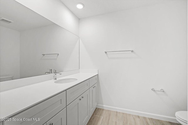 1305 Harper Blvd SW, Palm Bay, FL 32908 - bathroom featuring toilet, vanity, wood finished floors, and baseboards