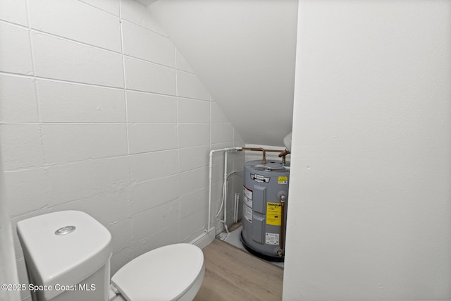 bathroom featuring toilet, vaulted ceiling, wood finished floors, and electric water heater