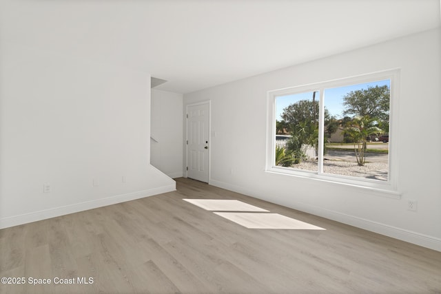 spare room featuring light wood-type flooring and baseboards