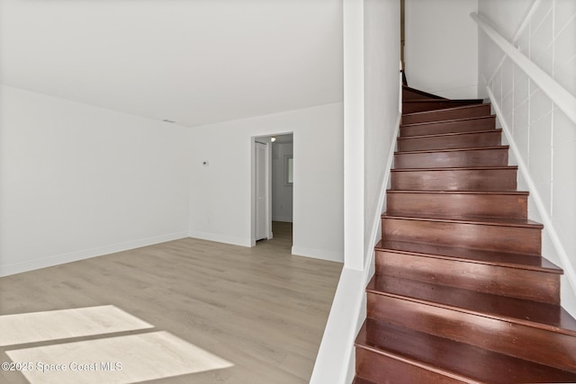 stairway with wood finished floors and baseboards