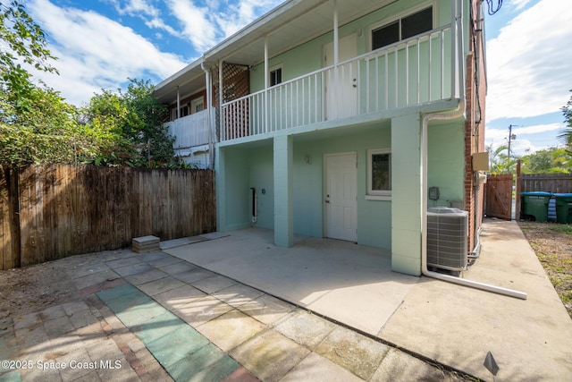 rear view of property featuring a fenced backyard, a patio, a balcony, and central air condition unit