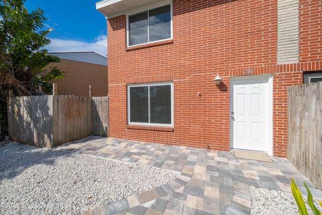 rear view of house featuring a patio area, fence, and brick siding