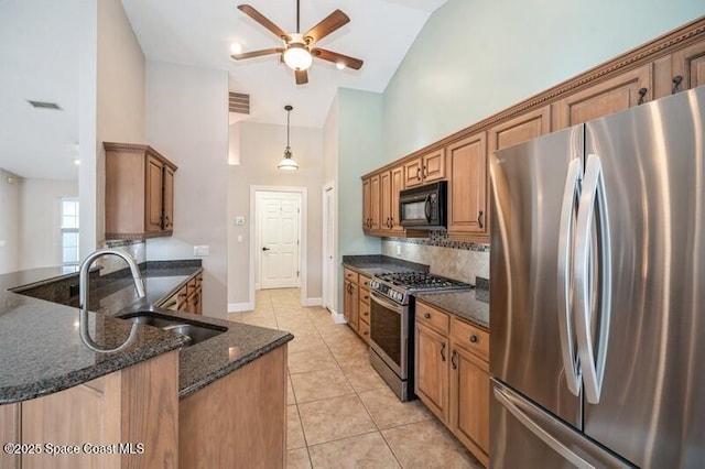 kitchen with sink, hanging light fixtures, light tile patterned floors, dark stone countertops, and stainless steel appliances