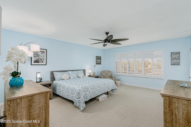 bedroom with a ceiling fan, light carpet, a textured ceiling, and baseboards