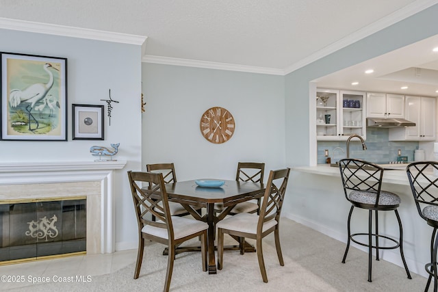 dining area featuring ornamental molding, a glass covered fireplace, and baseboards