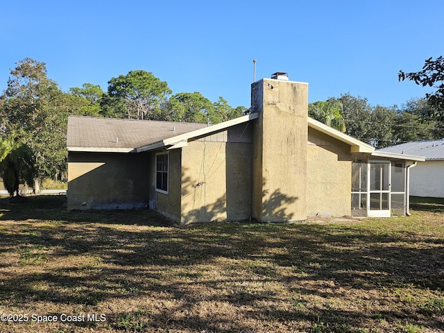 view of home's exterior with a yard and a sunroom