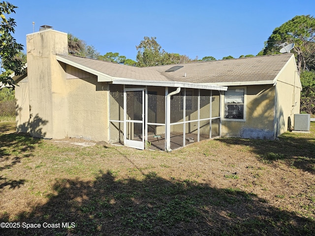 back of house with central AC unit, a lawn, and a sunroom