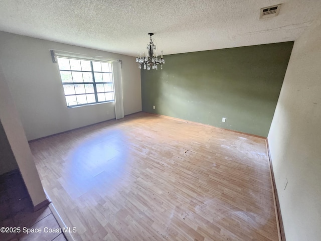 unfurnished dining area with a notable chandelier, a textured ceiling, and light hardwood / wood-style flooring