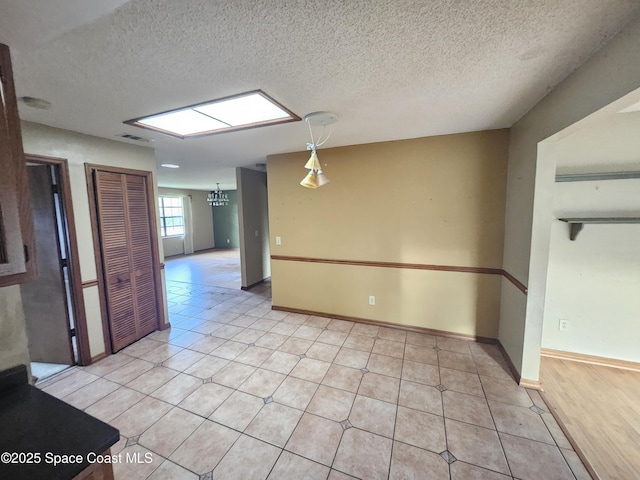 unfurnished room with light tile patterned floors, a notable chandelier, and a textured ceiling