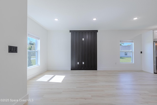 unfurnished room with recessed lighting, plenty of natural light, and light wood finished floors