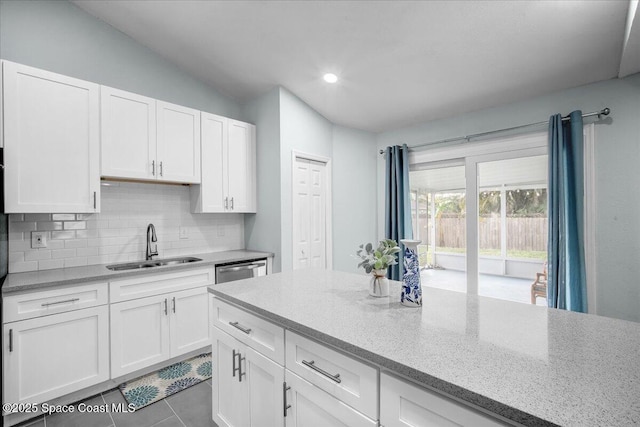 kitchen with light tile patterned flooring, sink, white cabinets, backsplash, and light stone counters