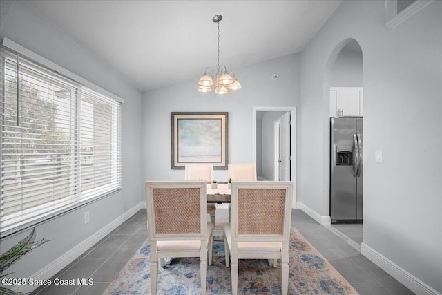 tiled dining area with lofted ceiling and a chandelier