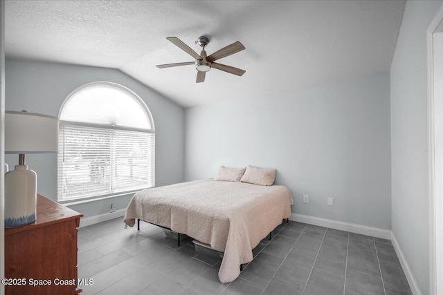 bedroom with ceiling fan, vaulted ceiling, and a textured ceiling