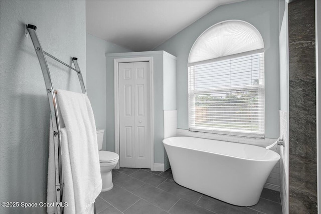 bathroom featuring tile patterned flooring, a bathing tub, and toilet